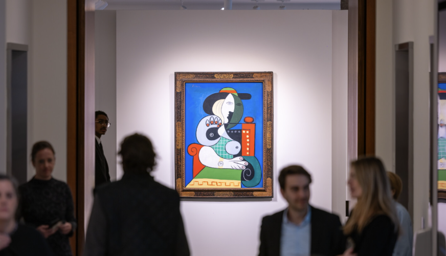 Visitors talking in front of a framed Picasso hung alone on a white gallery wall at a pre-sale view